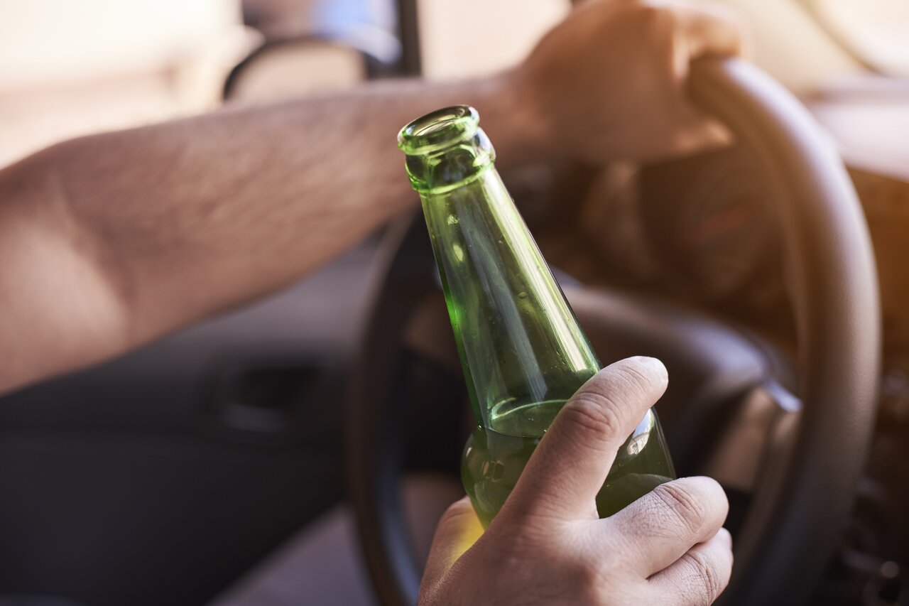 rsz man driving a car while holding a bottle of beer 2023 11 27 05 24 02 utc